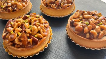 Nuss-topped Tartes auf einer schwarzen Unterlage angeordnet.