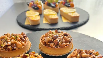 Köstliche Törtchen mit Nüssen und Früchten auf Platten.