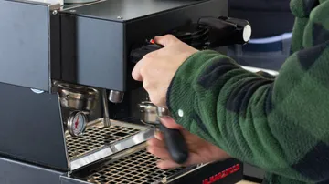 Ein Barista bedient eine Espressomaschine in einem Café.