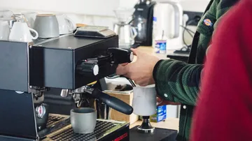 Espresso machine brews coffee in a modern café environment.