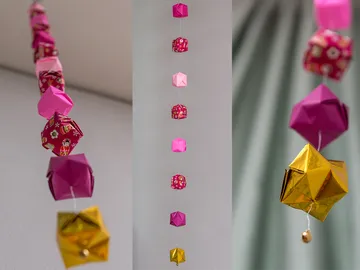 Bunte Origami-Objekte hängen dekorativ an einer Schnur.