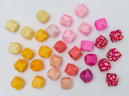 Bunte Origami-Stücke liegen auf einem weißen Hintergrund.