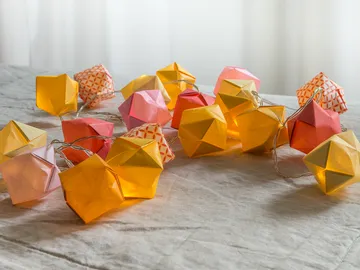 Bunte Papierlaternen liegen auf einem hellen Untergrund.