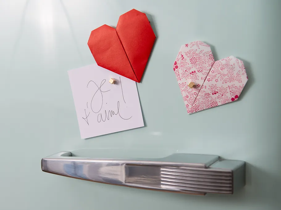 Red and pink origami hearts hang on refrigerator door