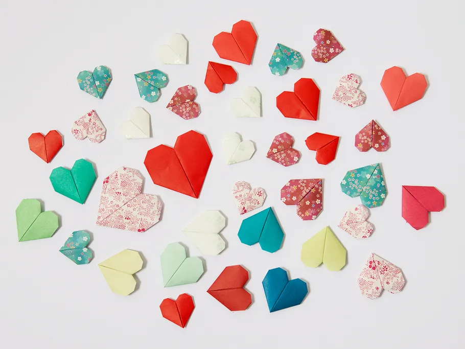 Colourful origami hearts lie on a white background.