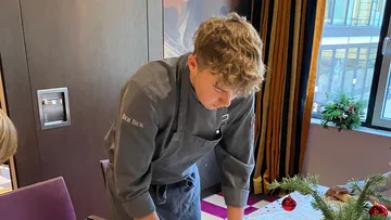 A boy in work clothes sets a table.