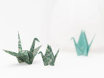 Paper cranes stand together on a white table.