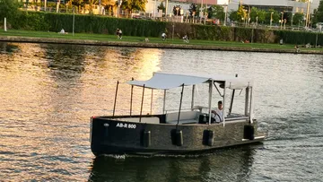 Partyboot mit Überdachung und Sonnensegel, das auf dem Fluss segelt.