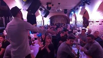 A man speaks to an audience in a nightclub.