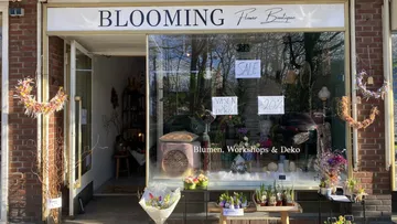 Blumenladen zeigt Dekorationen; Verkäuferin gestaltet das Schaufenster.