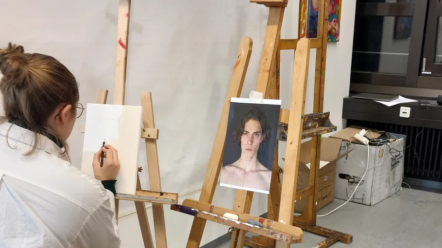 Eine Künstlerin skizziert ein Modell an der Staffelei.