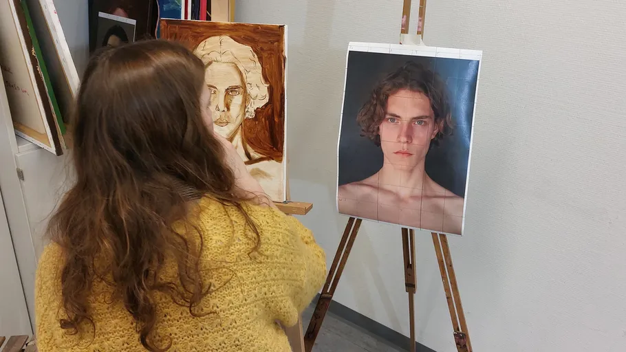 Artist painting a portrait from a reference photo.