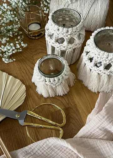 Vases decorated with macrame on a wooden table.