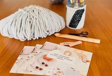 Wool, crochet hook and instructions on a wooden table.