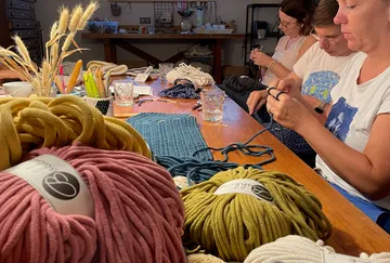 There are balls of yarn on the table, people are working on handicrafts.