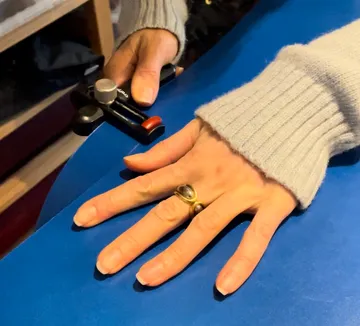 Hand hält Werkzeug auf blauer Fläche, konzentriert gearbeitet.