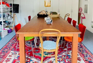 Holztisch mit bunten Stühlen in einem kreativen Raum.