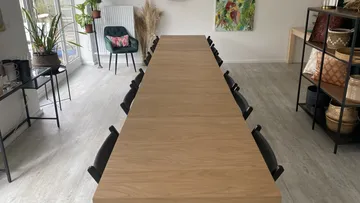 Long wooden table with chairs in a bright room.