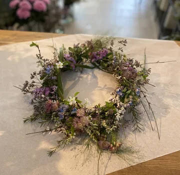 Floral wreath with purple, white blossoms on paper.