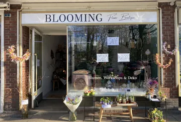 Flower boutique storefront with sale signs and decorations.