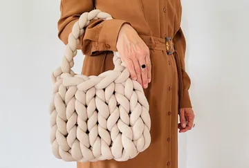 Eine geflochtene Tasche wird von einer Person gehalten.