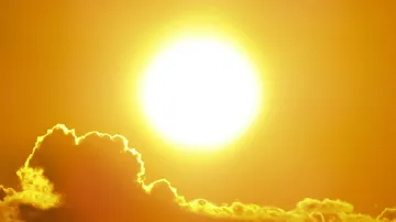 Die Sonne strahlt hell über einer gelben Wolkenlandschaft.