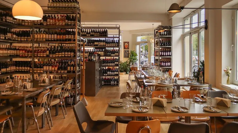 Ein Restaurant, gedeckte Tische, Regale mit Weinflaschen.