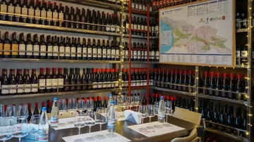 Shelf with wine bottles, table set for tasting.