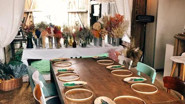 A wooden table with cutlery surrounded by floral arrangements.