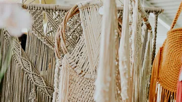 Close-up of handmade macrame wall hangings in various designs and patterns, hung in a creative showroom.
