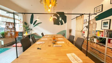 Wooden table with chairs surrounded by plants and art.