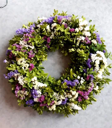 Blumenkranz hängt dekorativ an grauem Hintergrund.
