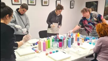 Group coaching: Participants paint at tables with bright colors.