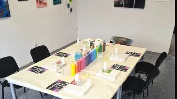 Tisch mit Farben und Leinwänden in kreativem Raum.