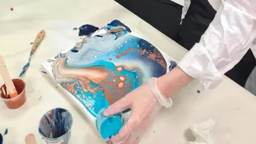Paints are poured onto a canvas, creative activity.