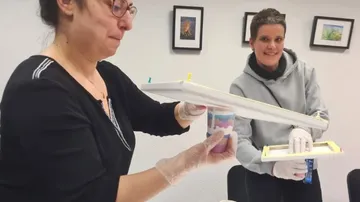 Two women are working on an art activity using colors.