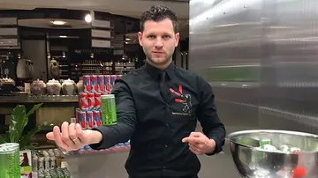 A bartender shows a can in a sales environment.