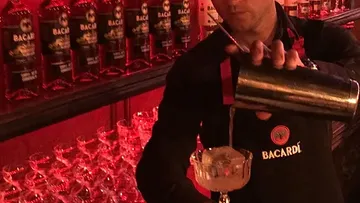 Bartender pours a cocktail into a glass.