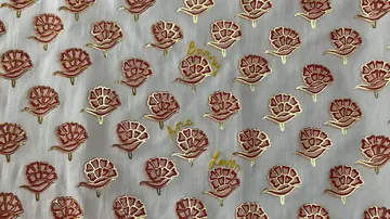 Rote Blumenmuster auf weißem Stoff, gleichmäßig angeordnet.