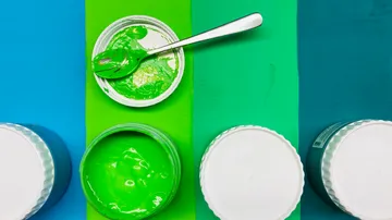 Grüne Farbe in einer Schüssel wird mit einem Löffel gemischt.