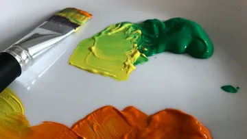 Pinsel liegt auf einer Palette mit bunten Farben.