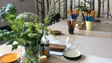 Blumen und Bastelmaterial stehen auf einem Tisch.