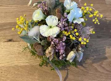 Bunter Trockenblumenstrauß auf Holztisch.