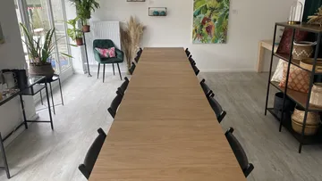 Langer Tisch mit Stühlen in hellem, modernen Raum.