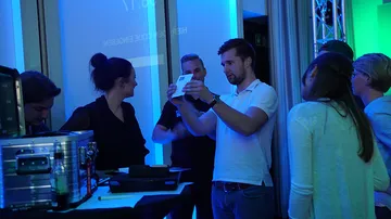 Men and women interact with technology at an event.