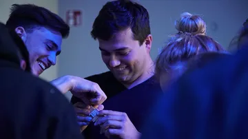 Junge Menschen lachen und tauschen etwas in gedämpfter Beleuchtung.