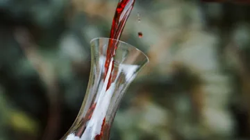 Red wine is poured from a carafe into a glass.