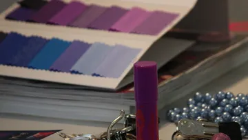 Farbfächer liegt daneben, Lippenstift steht auf Tisch, Schmuck.