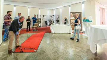 Mann puttet auf rotem Teppich in einer Veranstaltungslocation.