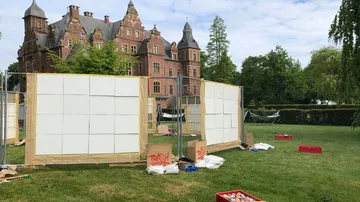 Leere Wände stehen auf einer Wiese vor einem Schloss.